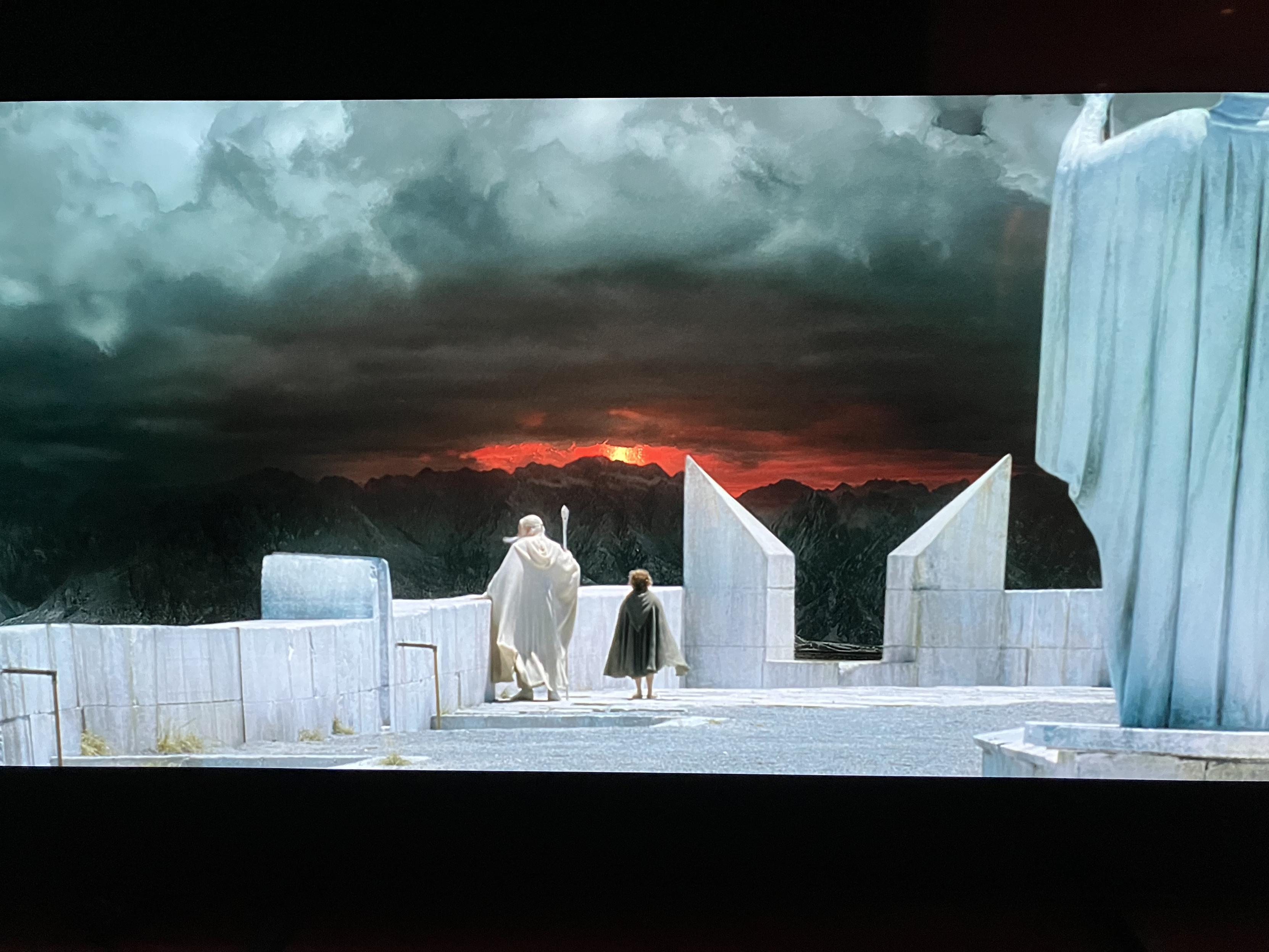 Gamdalf The White and Pippin Took standing at the top of a white stone castle, looking at a dark foreboding horizon.