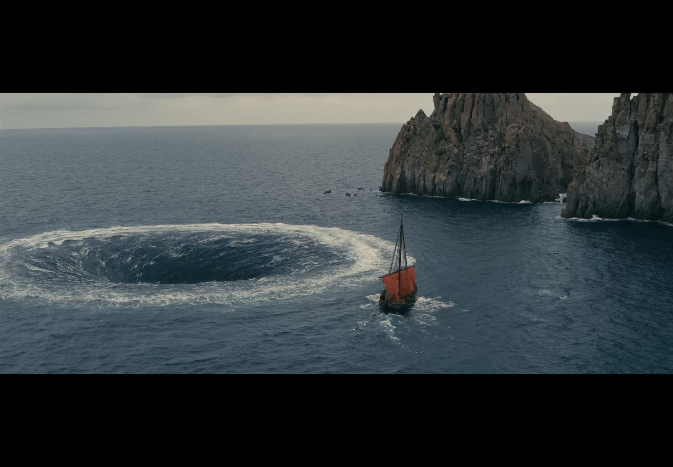 A picture of an ancient greek boat passing by a whirlpool and some rocks. It's broad daylight and the whirlpool looks pretty fake.